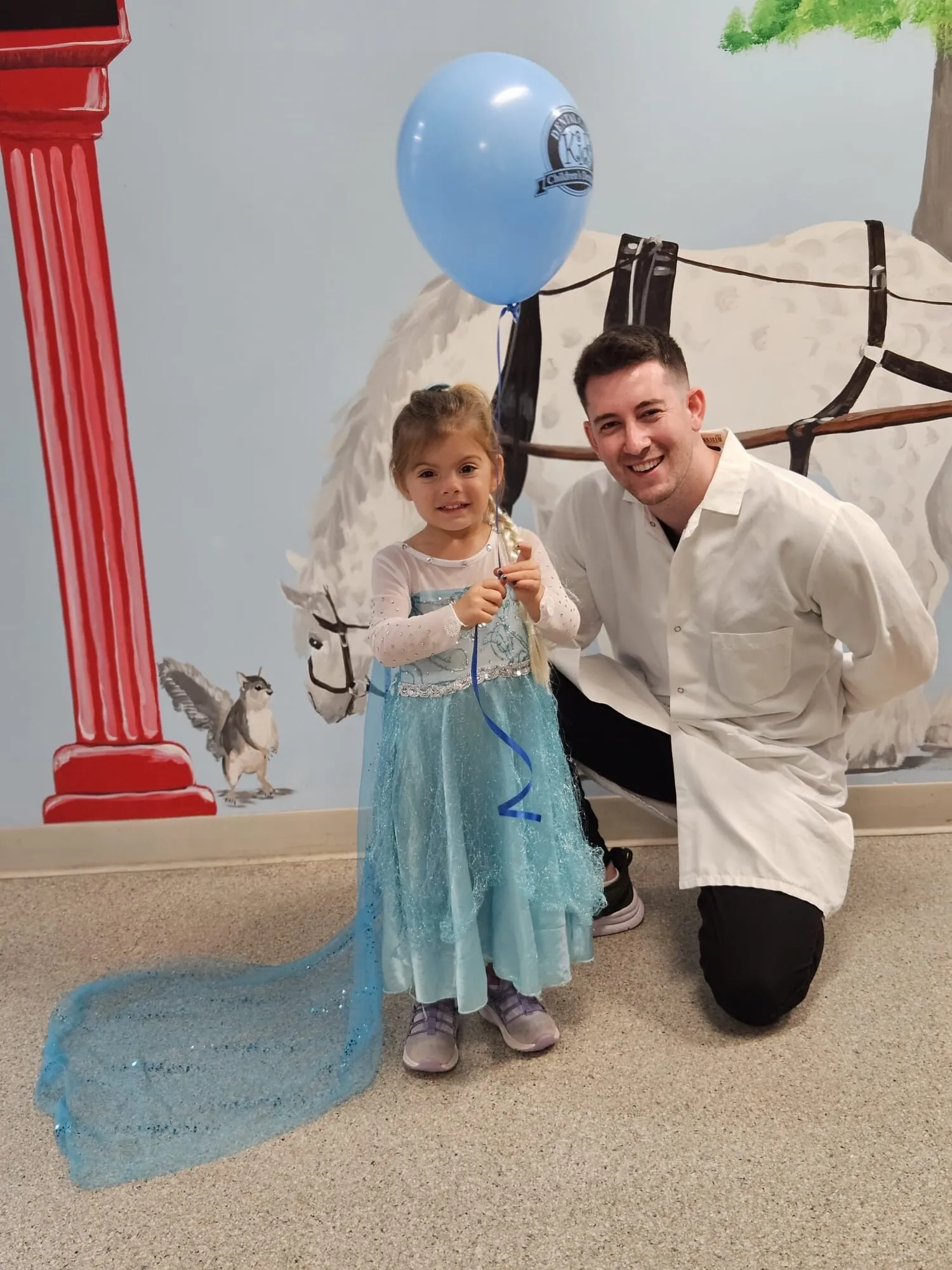 Happy little girl in a princess dress with her dentist at Dental Care Kids